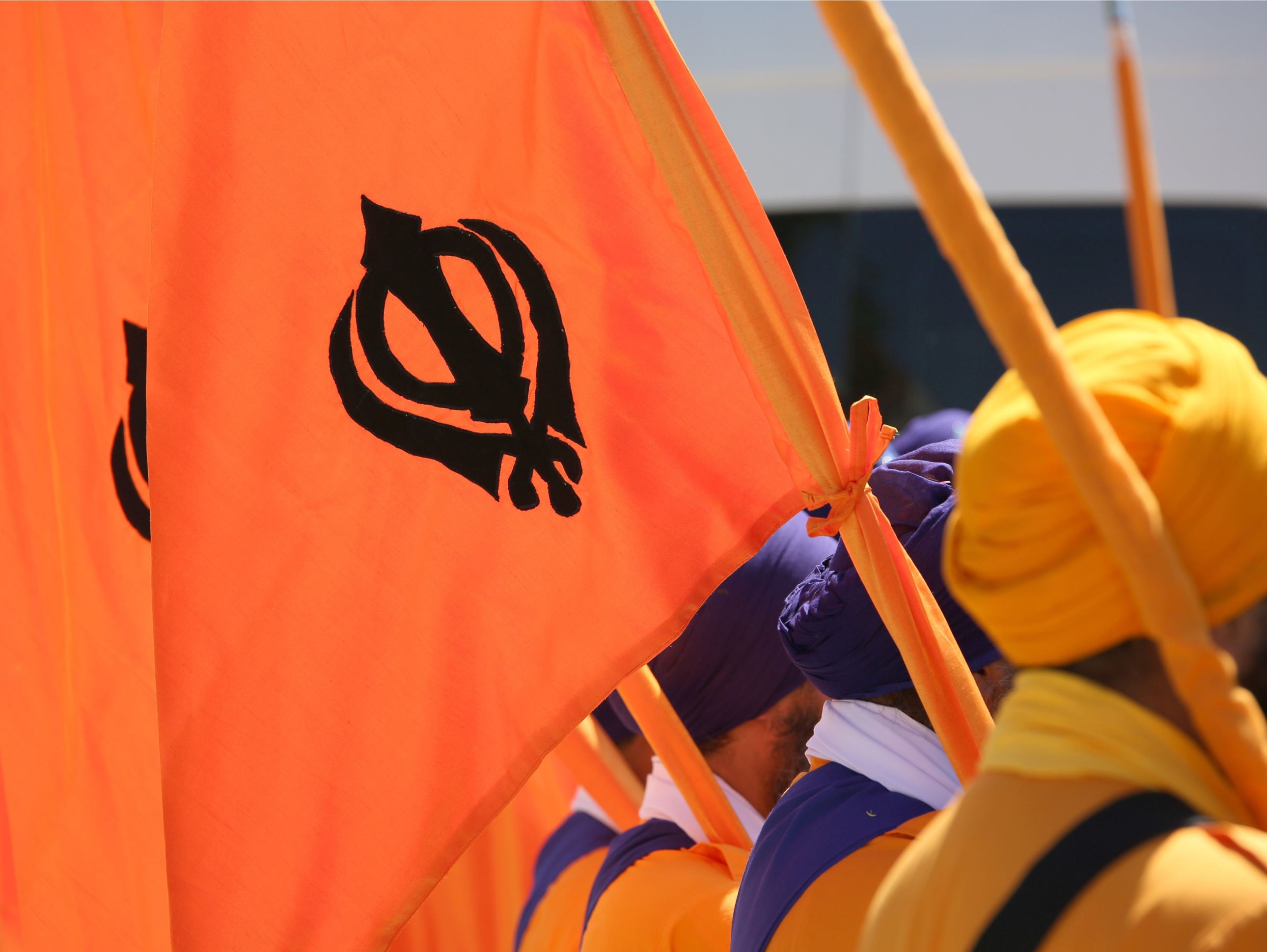 Orange flag with symbol of the Sikh religion called KHANDA formed by two scimitars and men with turbans