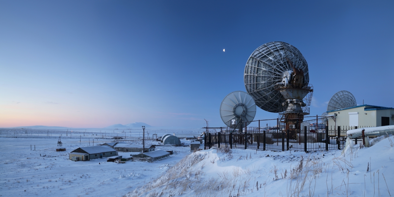 Winter panorama with large satellite dishes. Telecommunications in the Arctic. Industrial landscape with antennas. Morning twilight. Location place: Anadyr, Chukotka, Siberia, Far East of Russia.